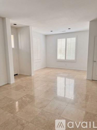 A spacious room with tiled flooring and a window with blinds.