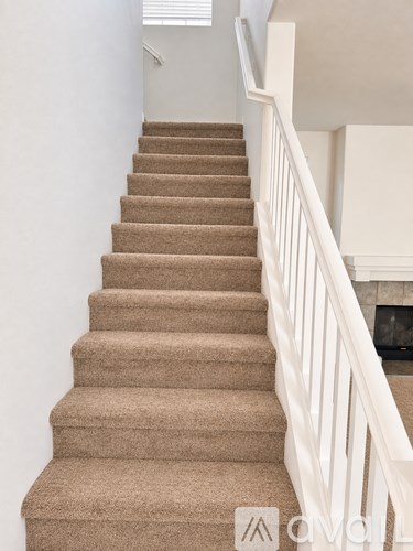 A beige carpeted staircase with white railings.