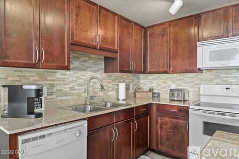 A kitchen with brown cabinets and a white dishwasher.
