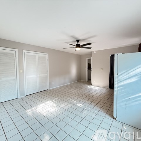 A spacious room with a ceiling fan and tiled flooring.
