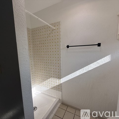 A white tiled shower with a black grab bar.