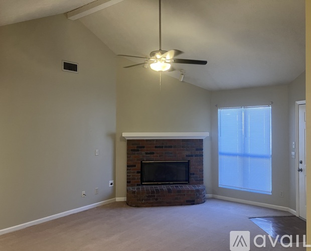 A living room with a fireplace and a ceiling fan.