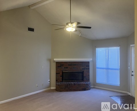 A living room with a fireplace and a ceiling fan.
