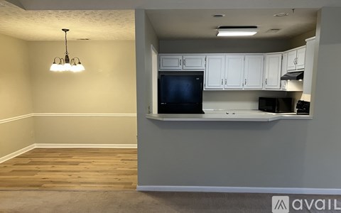 A kitchen area with a black fridge and white cabinets.