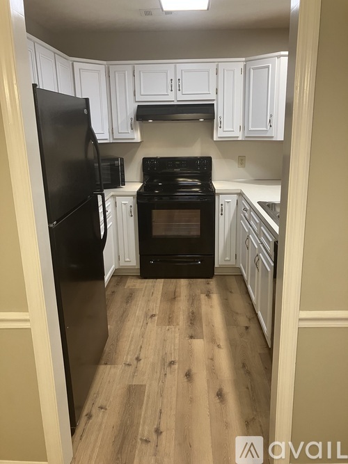 A kitchen with black appliances and white cabinets.
