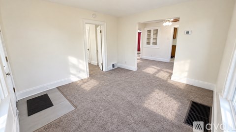 A spacious room with white walls and a carpeted floor.