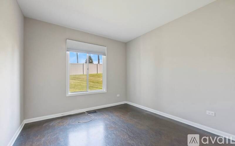 A room with a large window and a view of a tree and a building outside.