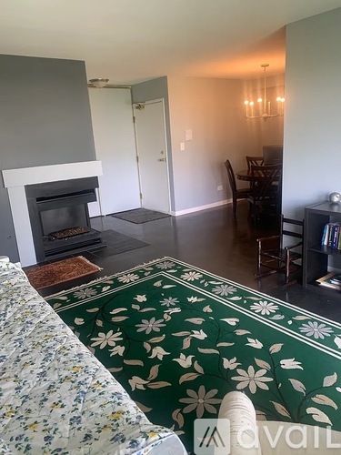 A living room with a fireplace and a green floral rug.