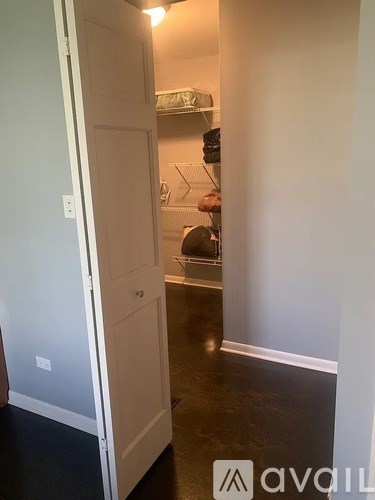 A hallway with a door on the left and a kitchen area on the right.