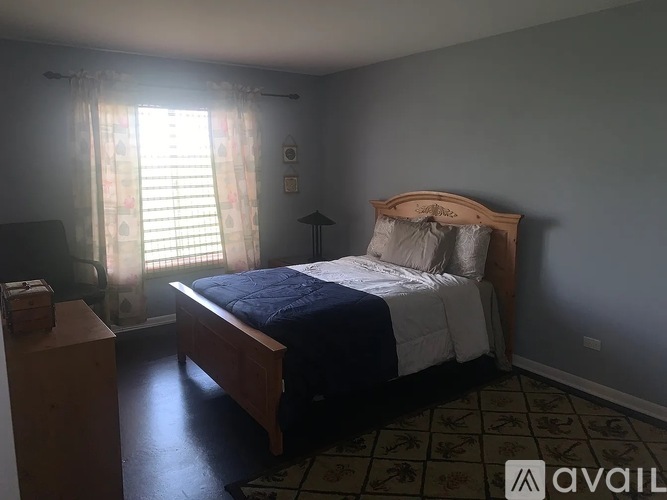 A bedroom with a bed, nightstand, and window with curtains.