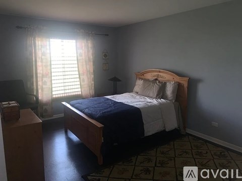A bedroom with a bed, nightstand, and window with curtains.