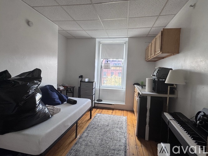 A bedroom with a bed, desk, and window.