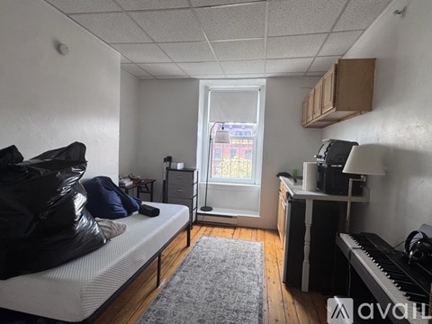 A bedroom with a bed, desk, and window.