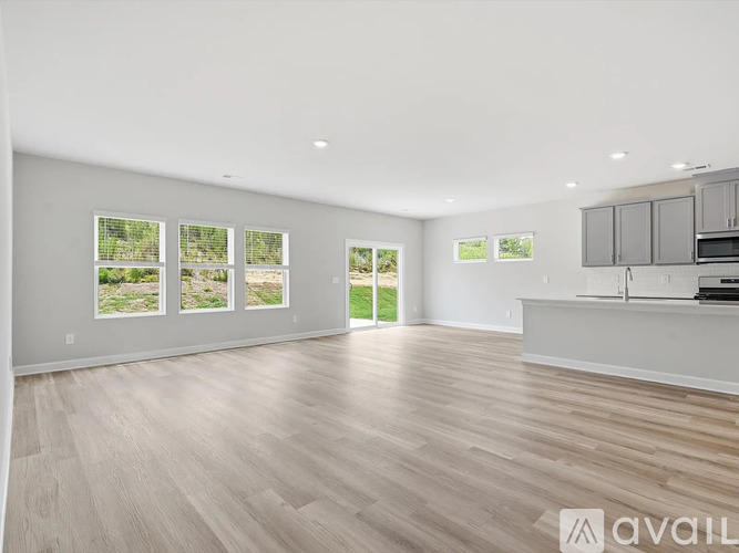 A spacious room with wooden flooring and large windows.