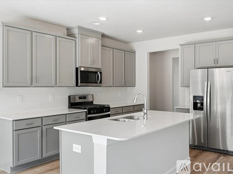 A modern kitchen with a white countertop and stainless steel appliances.