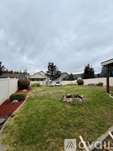 A backyard with a white fence and a small tree.