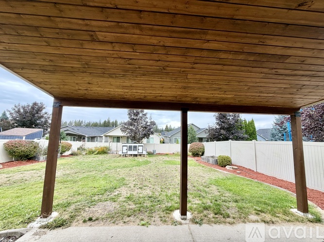 A wooden covered patio area with a view of a residential neighborhood.