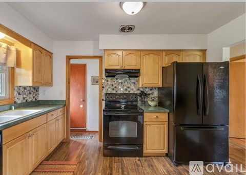 A kitchen with wooden cabinets and black appliances.