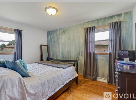 A bedroom with a bed, a chair, and a window with curtains.
