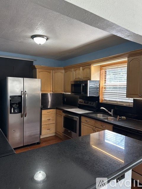 A kitchen with a black counter top and stainless steel appliances.