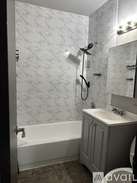 A bathroom with a marble wall and a white bathtub.