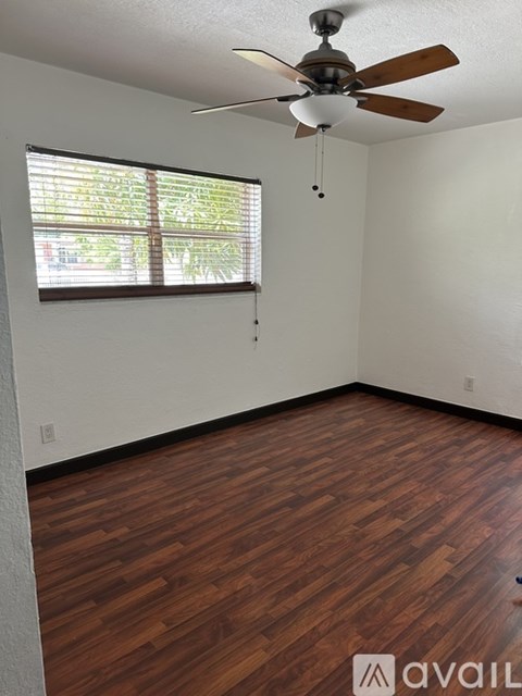 A room with a ceiling fan and wooden flooring.