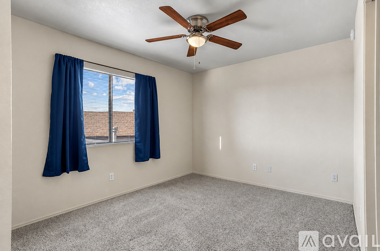 A room with a ceiling fan and a window with blue curtains.
