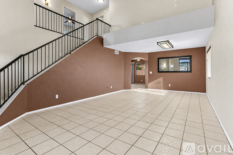 A spacious room with a staircase and a flat screen TV.