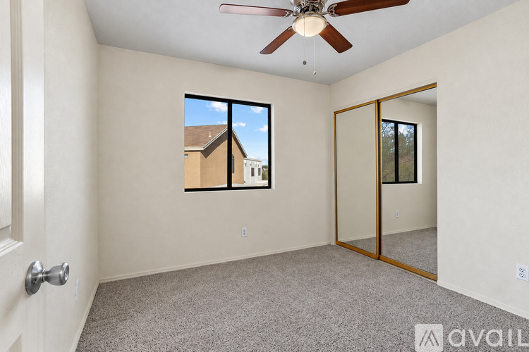 A room with a ceiling fan and a window overlooking a building.