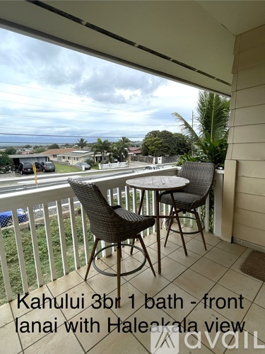 A balcony with a table and chairs overlooking a residential area.