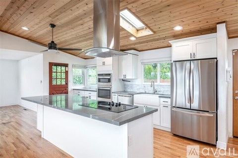 A modern kitchen with a wooden ceiling and stainless steel appliances.