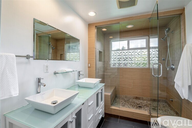 A modern bathroom with a glass shower stall and a white sink.