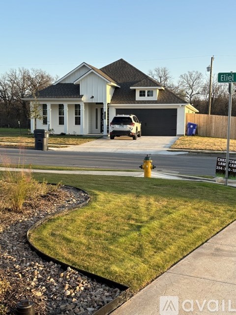 A white house with a garage and a car parked in front.