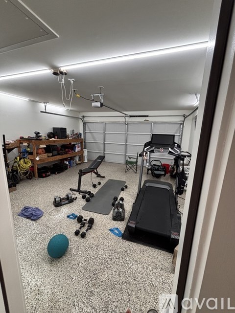 A gym with a variety of equipment including weights, a bench, and a treadmill.