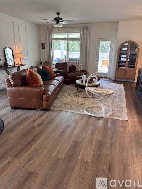 A living room with a brown leather couch and a wooden floor.