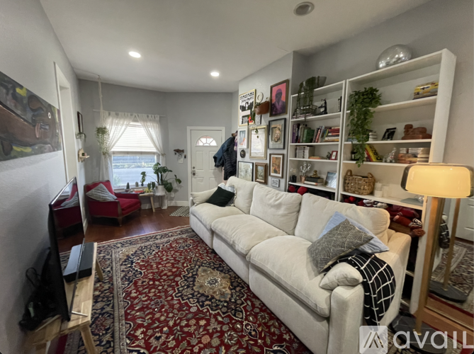A living room with a white couch and a red rug.