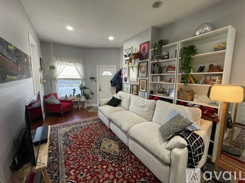 A living room with a white couch and a red rug.