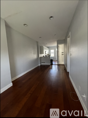 A long hallway with wood floors and white walls.