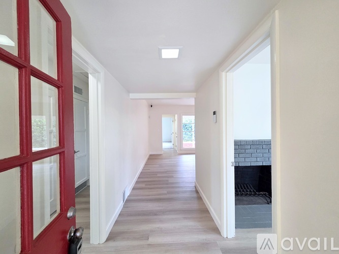 A hallway with a red door and a fireplace.