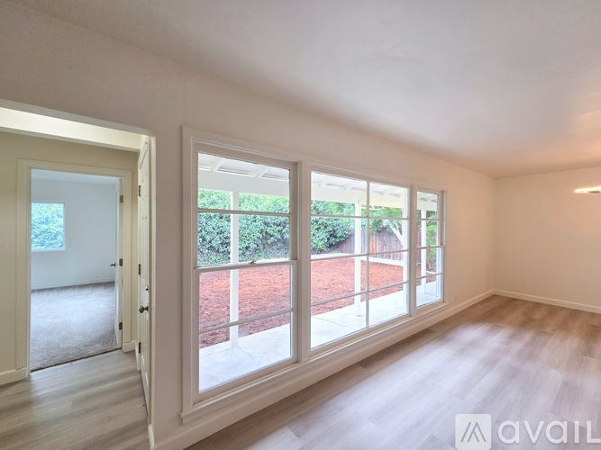 A room with a view of a garden through the windows.