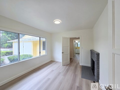 A spacious living room with a fireplace and a view of a yellow building outside the window.