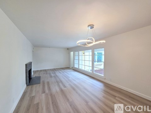 A spacious room with wooden flooring and a large window.