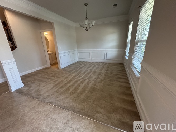 A room with a carpeted floor and a chandelier hanging from the ceiling.