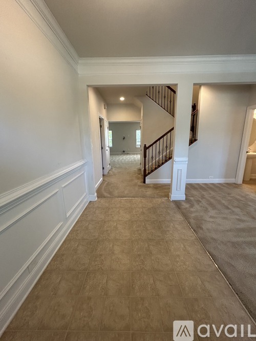 A hallway with a staircase and a carpeted floor.