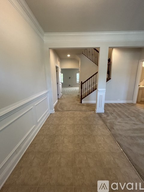 A hallway with a staircase and a carpeted floor.