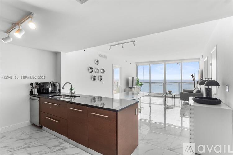 A modern kitchen with a large island and a view of the ocean.