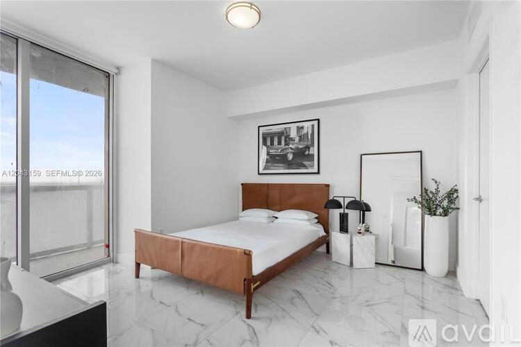 A bedroom with a large bed and a framed picture on the wall.