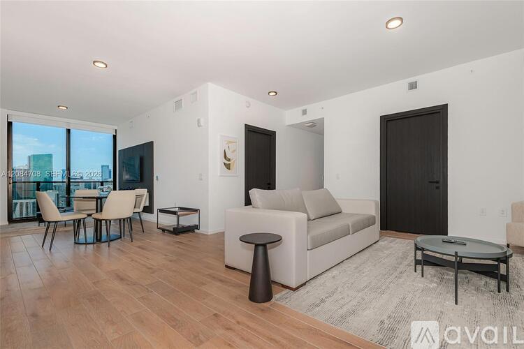 A modern living room with a large couch, a coffee table, and a dining table with chairs.