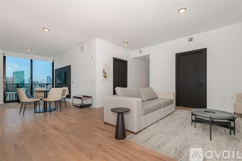 A modern living room with a large couch, a coffee table, and a dining table with chairs.