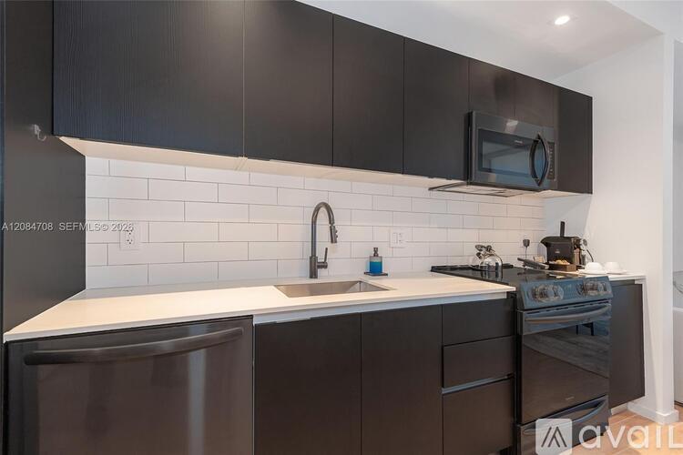A kitchen with black cabinets and a white countertop.